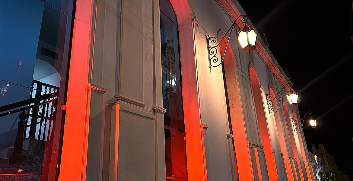 Luzes externas do Paço Municipal refletem a cor vermelha, em menção à campanha